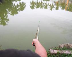 um homem sentado na margem do rio e pescando, verão ao ar livre. lazer sazonal. pescaria. pesca. foto