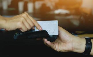 homem usando máquina de furto de cartão de crédito para vender produtos na loja para clientes. conceito de gastos via cartão de crédito. foto
