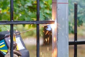 faíscas chama e arco de solda elétrica ao soldar uma cerca de metal. foto