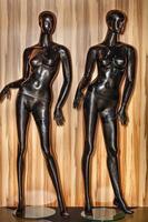 dois manequins pretos em um fundo de madeira para exibir roupas em uma loja. foto