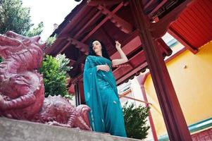 retrato da linda garota brumette indiana ou modelo de mulher hindu contra a casa tradicional japonesa e a figura do dragão. foto