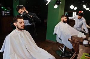 homem barbudo bonito na barbearia, barbeiro no trabalho. foto