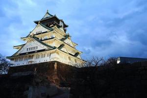 castelo de osaka em osaka, japão, iluminado por holofotes durante o anoitecer. foto