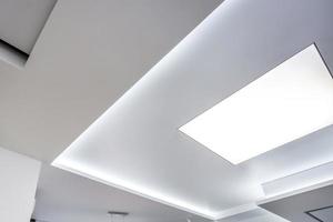 lâmpadas de halogênio no teto suspenso e construção de drywall em sala vazia em apartamento ou casa. tecto falso branco e forma complexa. foto