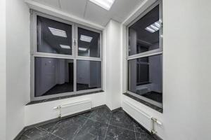 grandes janelas no interior da sala vazia sem mobília na cor branca em apartamentos modernos, escritório ou clínica foto