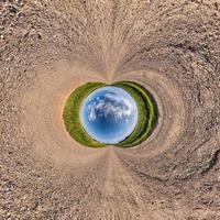 inversão do pequeno planeta transformação do panorama esférico 360 graus. vista aérea abstrata esférica na estrada de cascalho com lindas nuvens impressionantes. curvatura do espaço. foto