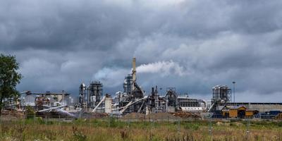 tubos de serraria de planta de empresa de marcenaria contra um céu cinzento sombrio. conceito de poluição do ar. panorama da paisagem industrial poluição ambiental resíduos da usina termelétrica foto