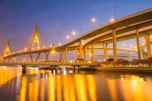 ponte suspensa moderna e rodovia curvada ribeirinha na cena do crepúsculo com luz dourada foto