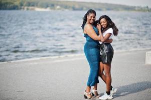 dois amigos de pele escura afro-americanos fêmeas. um deles modelo plus size, segundo slim. se divertindo e passando tempo juntos. foto