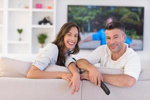 jovem casal no sofá assistindo televisão foto