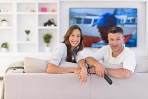 jovem casal no sofá assistindo televisão foto