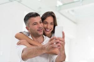 casal feliz usando celular em casa foto