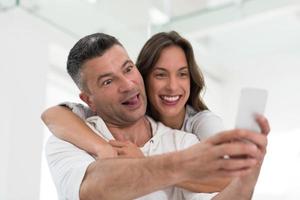 casal feliz usando celular em casa foto