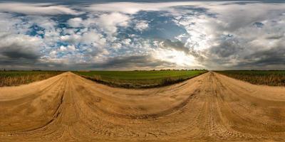 panorama hdri esférico completo sem costura vista de ângulo de 360 graus na estrada de cascalho entre campos no pôr do sol da noite de outono com nuvens impressionantes em projeção equirretangular, pronto para realidade virtual vr ar foto