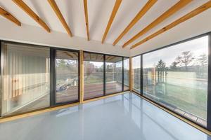 interior de apartamento vazio branco com janelas panorâmicas e teto de viga de madeira em casa de herdade de férias, com vista para a natureza na floresta foto