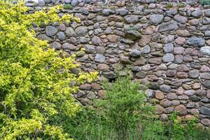 superfície de um velho muro de enormes pedras de um edifício destruído foto