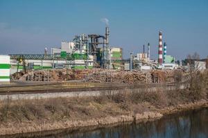 tubos de serraria de planta de empresa de marcenaria perto do rio. conceito de poluição do ar. paisagem industrial poluição ambiental resíduos de usina termelétrica foto