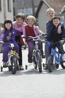 grupo infantil feliz aprendendo a dirigir bicicleta foto