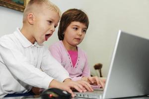 as crianças se divertem e jogam no computador portátil foto