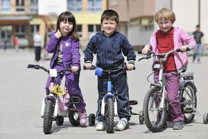 grupo infantil feliz aprendendo a dirigir bicicleta foto