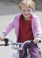 menina bonitinha dirigindo bicyle em dia ensolarado foto