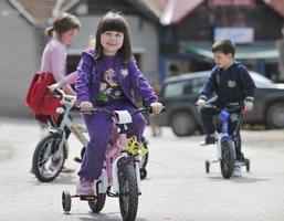 grupo infantil feliz aprendendo a dirigir bicicleta foto