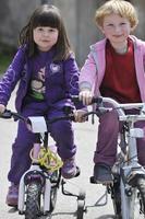 grupo infantil feliz aprendendo a dirigir bicicleta foto