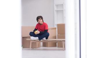 menino sentado na mesa com caixas de papelão ao redor dele foto