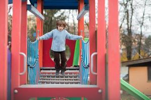 menino bonitinho se divertindo no playground foto