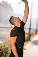 homem derramando água da garrafa na cabeça foto