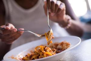 uma jovem afro-americana comendo macarrão foto