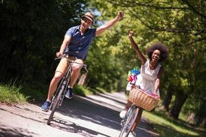 jovem casal multiétnico dando um passeio de bicicleta na natureza foto