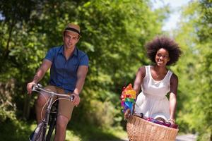 jovem casal multiétnico dando um passeio de bicicleta na natureza foto