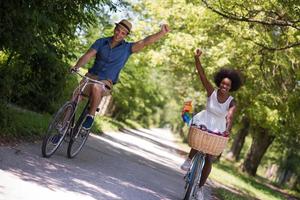 jovem casal multiétnico dando um passeio de bicicleta na natureza foto