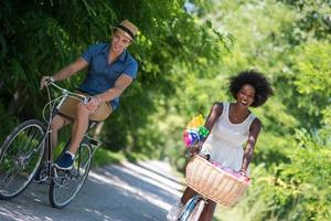 jovem casal multiétnico dando um passeio de bicicleta na natureza foto