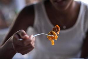 uma jovem afro-americana comendo macarrão foto