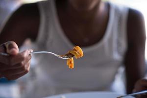 uma jovem afro-americana comendo macarrão foto