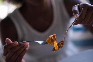 uma jovem afro-americana comendo macarrão foto