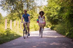 jovem casal multiétnico dando um passeio de bicicleta na natureza foto