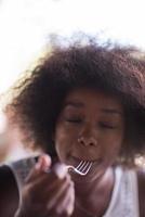 uma jovem afro-americana comendo macarrão foto