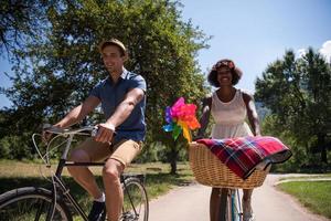 jovem casal multiétnico dando um passeio de bicicleta na natureza foto