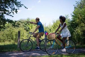 jovem casal multiétnico dando um passeio de bicicleta na natureza foto