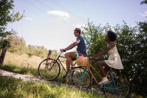 jovem casal multiétnico dando um passeio de bicicleta na natureza foto