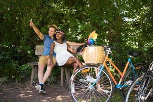 jovem casal multiétnico dando um passeio de bicicleta na natureza foto