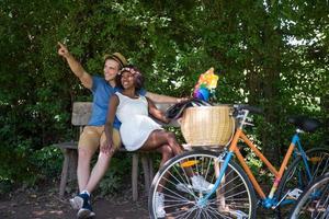 jovem casal multiétnico dando um passeio de bicicleta na natureza foto