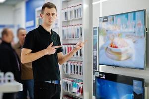 vendedor homem consultor profissional em loja de tecnologia ou loja estande perto de tv inteligente. foto