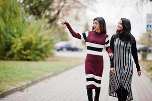 retrato de dois jovens lindos indianos ou adolescentes do sul da Ásia em vestido andando juntos na rua. foto