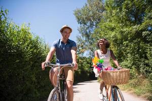 jovem casal multiétnico dando um passeio de bicicleta na natureza foto