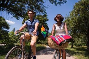 jovem casal multiétnico dando um passeio de bicicleta na natureza foto