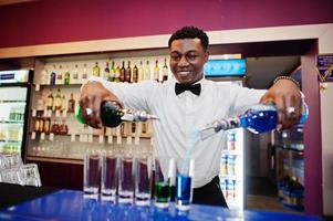 barman americano africano no bar fazendo coquetéis em tiros. preparação de bebidas alcoólicas. foto